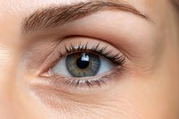 Close-up of woman's green eye with natural makeup and well-groomed eyebrow showing detailed iris patterns and long eyelashes for beauty concepts.