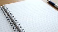 Open spiral notebook with blank lined pages and black pen on wooden desk surface ready for writing notes or journaling.