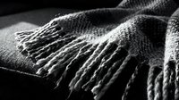 Close-up of soft woven fabric with fringed edges, showcasing textile detail and natural fibers for design and fashion projects.
