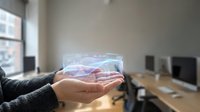 Businessman holding holographic data visualization with financial charts and graphs in modern office workspace for business analytics and technology presentation.