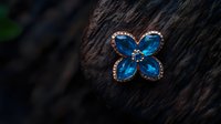 Elegant butterfly-shaped brooch with blue gemstones and crystal accents on dark wooden background, showcasing luxury jewelry craftsmanship and design detail.
