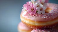 Pink glazed donuts topped with delicate cherry blossoms and pearl sprinkles on soft blue background for bakery menu dessert photography.