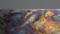 Colorful abstract textured surface with metallic paint layers creating organic patterns in purple, gold and bronze tones for artistic backgrounds.