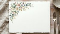 Blank white card with watercolor floral corner arrangement featuring eucalyptus, roses and greenery on wooden table with place setting for wedding invitations, stationery design and greeting cards.