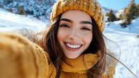 Young mixed race woman with bright smile wearing yellow knitted beanie and scarf enjoying winter day in snowy mountains, close up portrait with natural lighting.