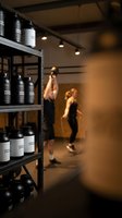 Modern fitness studio interior with supplement bottles on shelves and blurred athletes training in background for health and wellness marketing.