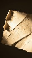Ancient stone fragment with weathered surface and natural cracks against dark background for archaeological and historical projects.