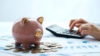 Pink piggy bank with coins and calculator on financial documents showing personal savings and budget planning for money management and investment goals.