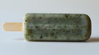 Green tea matcha popsicle with natural herbs and spices on wooden stick isolated on white background for summer dessert and healthy frozen treat concepts.