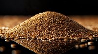 Golden brown coffee beans scattered in pile with mirror reflection on black glossy surface, dramatic lighting creates luxurious mood for gourmet food photography.