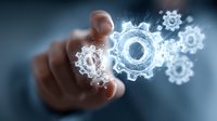 Hand touching glowing digital gear mechanisms representing automation, technology innovation and business process optimization in modern workplace.