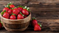 Fresh ripe strawberries in rustic wooden bowl against dark wooden background, selective focus with copy space for food photography.