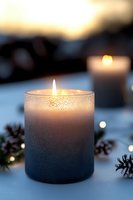 Glittery gradient candle burning with warm flame on winter table with pine cones, cozy evening atmosphere for holiday relaxation and home decor.