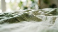 Crumpled linen fabric with green and white stripes in soft natural light, suitable for textile, home decor, and lifestyle design projects.
