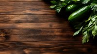 Fresh green cucumbers and parsley leaves arranged on dark rustic wooden background with copy space for menu or recipe design, top view layout.