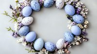 Easter wreath made with speckled blue and white eggs decorated with delicate spring blossoms and green twigs on light background, festive holiday arrangement.