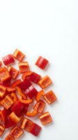Freshly chopped red bell pepper pieces scattered on a white background, showcasing vibrant color and texture for food and healthy eating concepts.