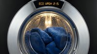 Modern washing machine drum with blue towels inside, eco wash cycle display visible, energy efficient laundry appliance for household cleaning and fabric care.