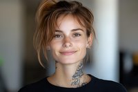 Young tattooed woman with blonde hair and nose piercing smiling warmly at camera in modern indoor setting for lifestyle and portrait photography.