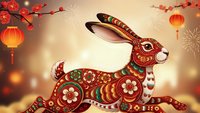 Ornate red rabbit with traditional floral patterns and decorative elements celebrating lunar new year with lanterns and cherry blossoms on warm background.
