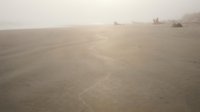 Serene ocean waves gently washing onto sandy beach shore during golden hour sunset with soft warm light reflecting on water surface creating peaceful coastal atmosphere.