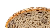 Artisan multigrain bread slice with sunflower seeds and pumpkin seeds showing airy texture and golden crust isolated on white background for food design.