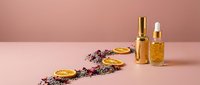 Luxury golden cosmetic bottles with dried lavender flowers on pink background for skincare and beauty product photography.