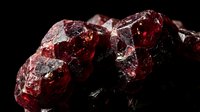 Raw red garnet gemstone cluster with crystalline formations on dark background for jewelry making and mineral collection displays.