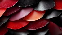 Overlapping scales of red and black leather creating textured pattern for fashion design, upholstery, or abstract background.