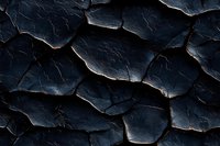 Dramatic dark cracked surface with glowing edges creates abstract pattern of fractured terrain. Deep shadows and highlights reveal natural texture formation.