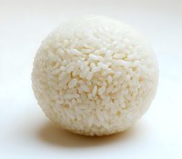 Round ball made of white jasmine rice grains on light background, macro food photography showing texture and detail for culinary and cooking concepts.