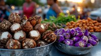 Fresh produce at farmers market stall featuring purple Asian eggplants and coconuts in metal bowls, with blurred background of vendors and other vegetables.