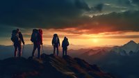Silhouettes of four hikers with backpacks standing on mountain peak at dramatic sunset, watching golden sun setting behind majestic mountain ranges in distance.
