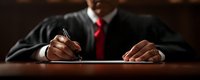 Professional businessman in dark suit signing important legal document with fountain pen at wooden desk in corporate office setting.