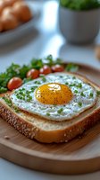 Sunny side up egg on toasted bread garnished with fresh herbs and black pepper, served with cherry tomatoes on wooden board. Fresh breakfast setting.