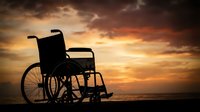 Silhouette of empty wheelchair against dramatic golden sunset sky with clouds, symbolizing disability awareness, accessibility, rehabilitation, and inclusive healthcare support.