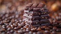 Stacked dark chocolate bars with nuts on scattered coffee beans background, macro food photography with selective focus and shallow depth of field.