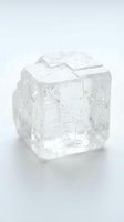 Clear quartz crystal cube with natural inclusions and geometric facets, isolated on white background for design and jewelry applications.