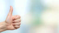Hand showing thumbs up gesture against soft blurred background expressing approval, success and positive feedback for business presentations.