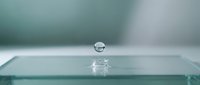 Water droplet bouncing on glass surface with splash effect, capturing motion and liquid dynamics for design and editorial projects.