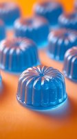 Blue translucent jelly desserts with ribbed dome shape arranged on orange surface, selective focus on single piece in foreground, soft dreamy food photography.