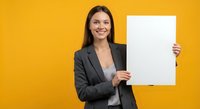 Professional businesswoman holding blank white paper sheet against vibrant yellow background for marketing presentations and corporate communications.