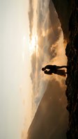 Silhouette of hiker standing on mountain peak during golden hour sunset with dramatic clouds and valley below for adventure and travel concepts.