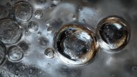 Shimmering air bubbles floating on water surface with metallic silver and gold reflections creating abstract macro photography.
