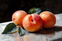 Fresh ripe apricots with green leaves on marble surface. Organic stone fruits for healthy eating, cooking, baking and food photography projects.
