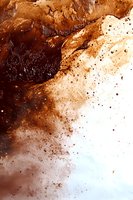 Abstract brown and copper watercolor splash with dark rich texture and scattered droplets on white background creates dramatic artistic effect.