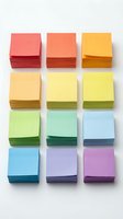 Colorful stacked sticky note pads arranged in a grid pattern on white background, showing rainbow spectrum from red to pink. Office supplies for organization.