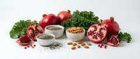Antioxidant-rich superfood collection with pomegranates, kale, nuts and seeds arranged on white background for healthy nutrition and wellness concepts.