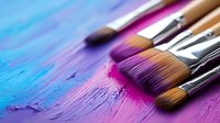 Paint brushes with colorful pink and blue acrylic paint strokes on artistic background, showing texture and creative process for painters and artists.