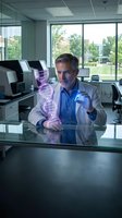 Mature Caucasian scientist examining holographic DNA double helix structure in modern laboratory office with digital technology for genetic research and biotechnology.